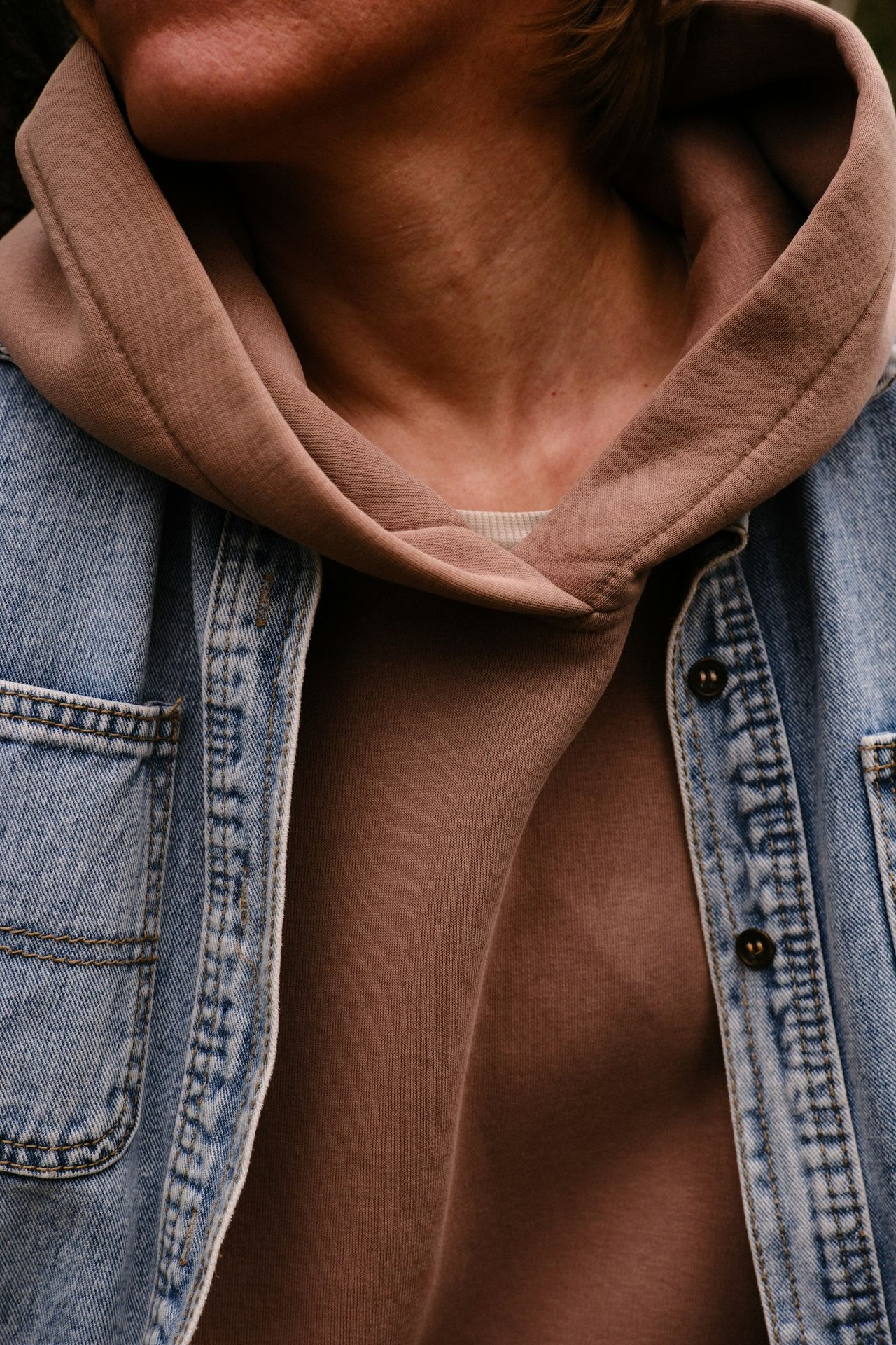 Person wearing a hoodie and denim jacket.